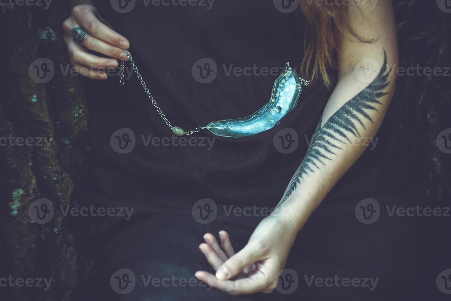 Close up lady with tattoo demonstrating pendant concept photo