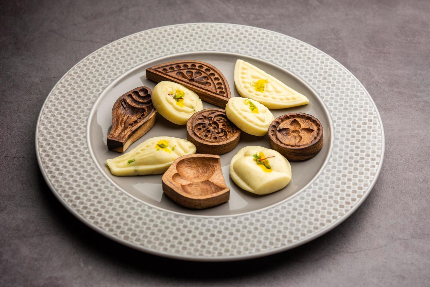 comida dulce sandesh o shondesh con moldes de madera en un plato foto