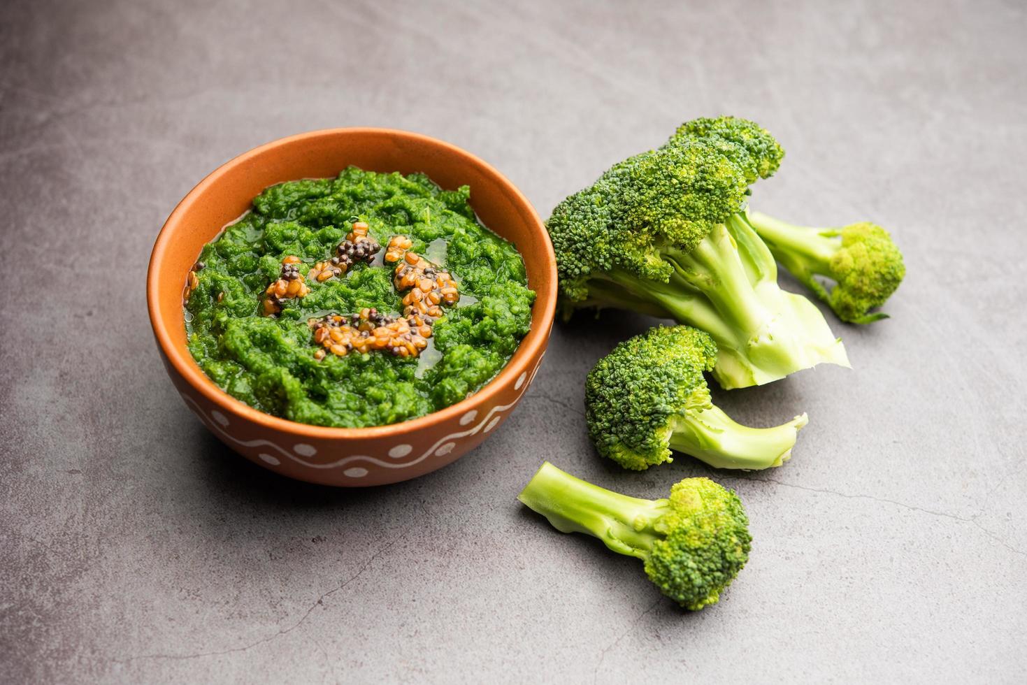 Fresh broccoli chutney or paste, puree in the bowl with raw pieces photo