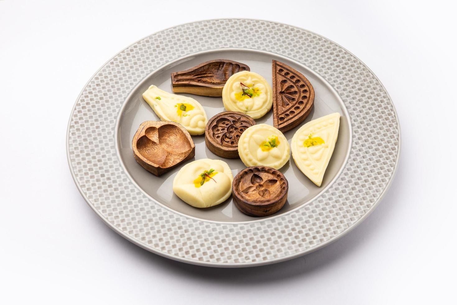 comida dulce sandesh o shondesh con moldes de madera en un plato foto