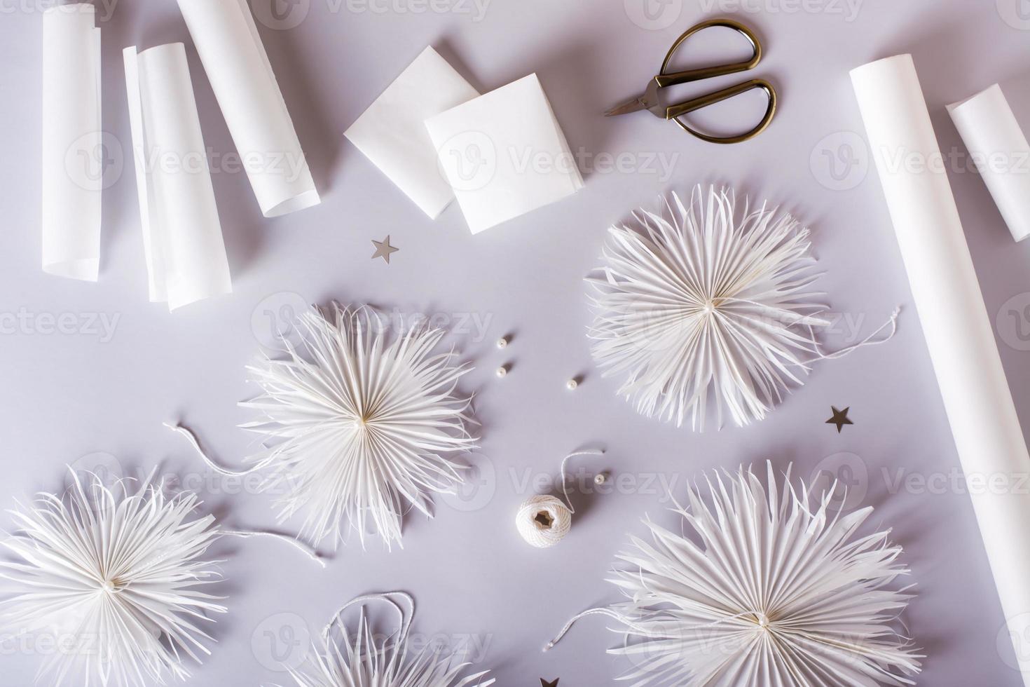 Original paper snowflakes with thread and bead on a gray background. Handmade decor. Top view photo