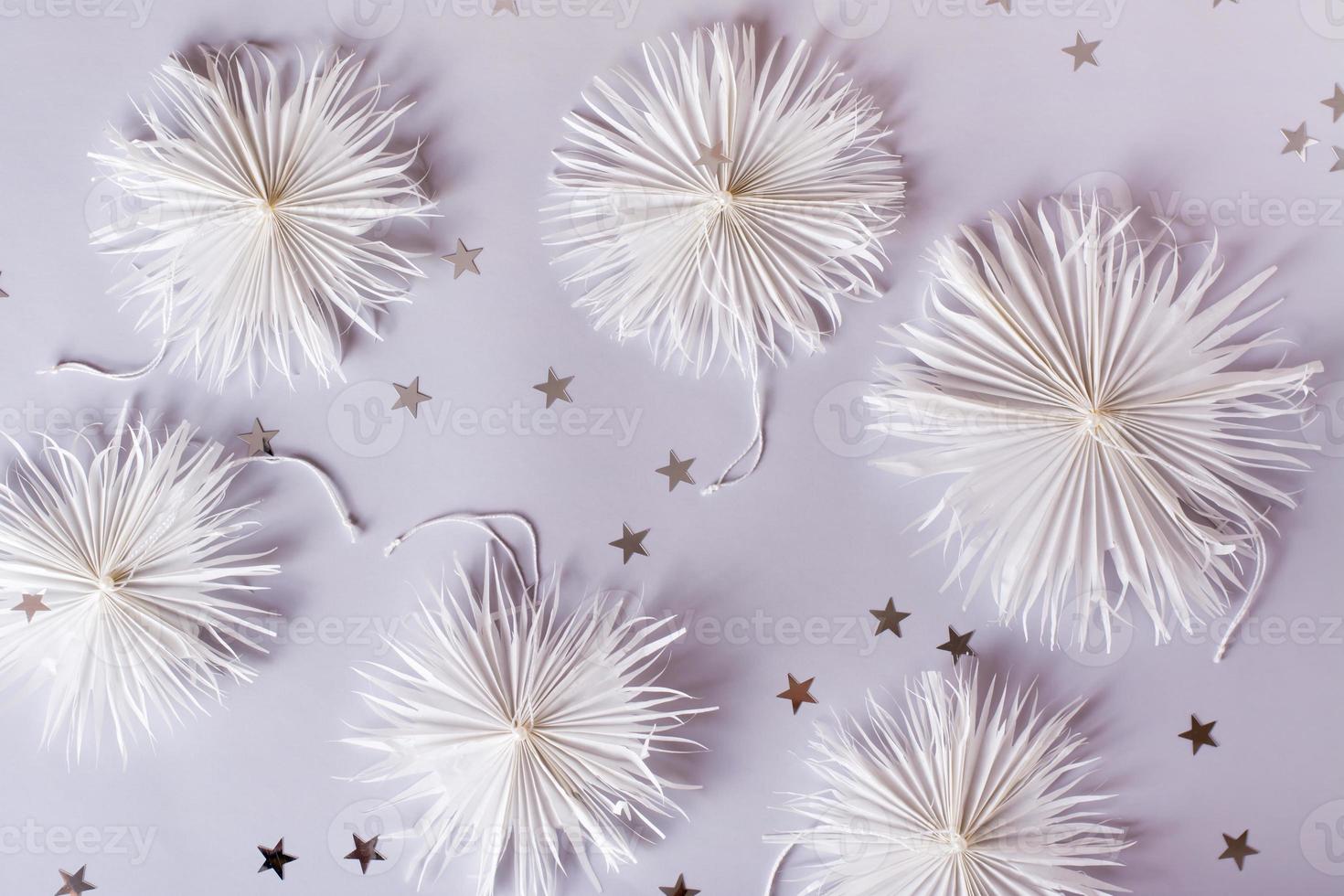 Simple Christmas paper snowflakes with a thread and a bead on a gray. Handmade decor. Top view photo