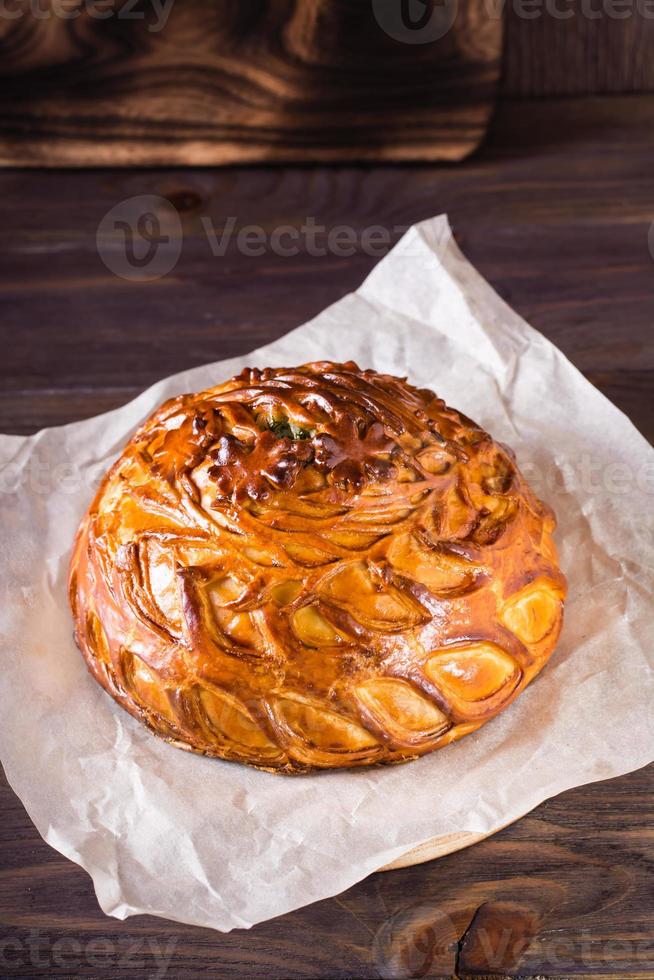 Homemade hearty kurnik pie with chicken, potatoes and rice on parchment. Vertical view photo