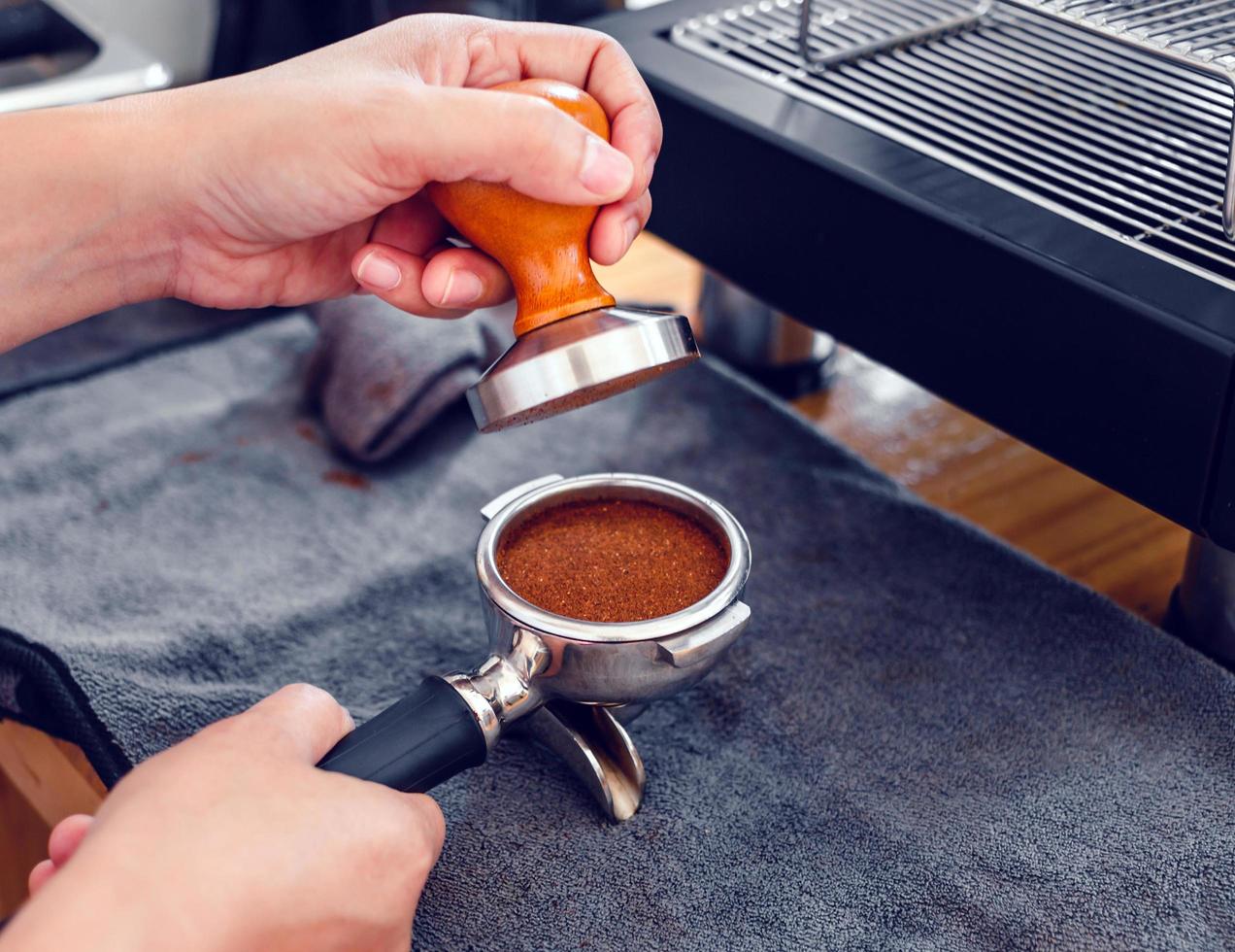 Barista cafe making coffee with manual presses ground coffee using tamper  on the wooden counter bar at the coffee shop 16586250 Stock Photo at  Vecteezy