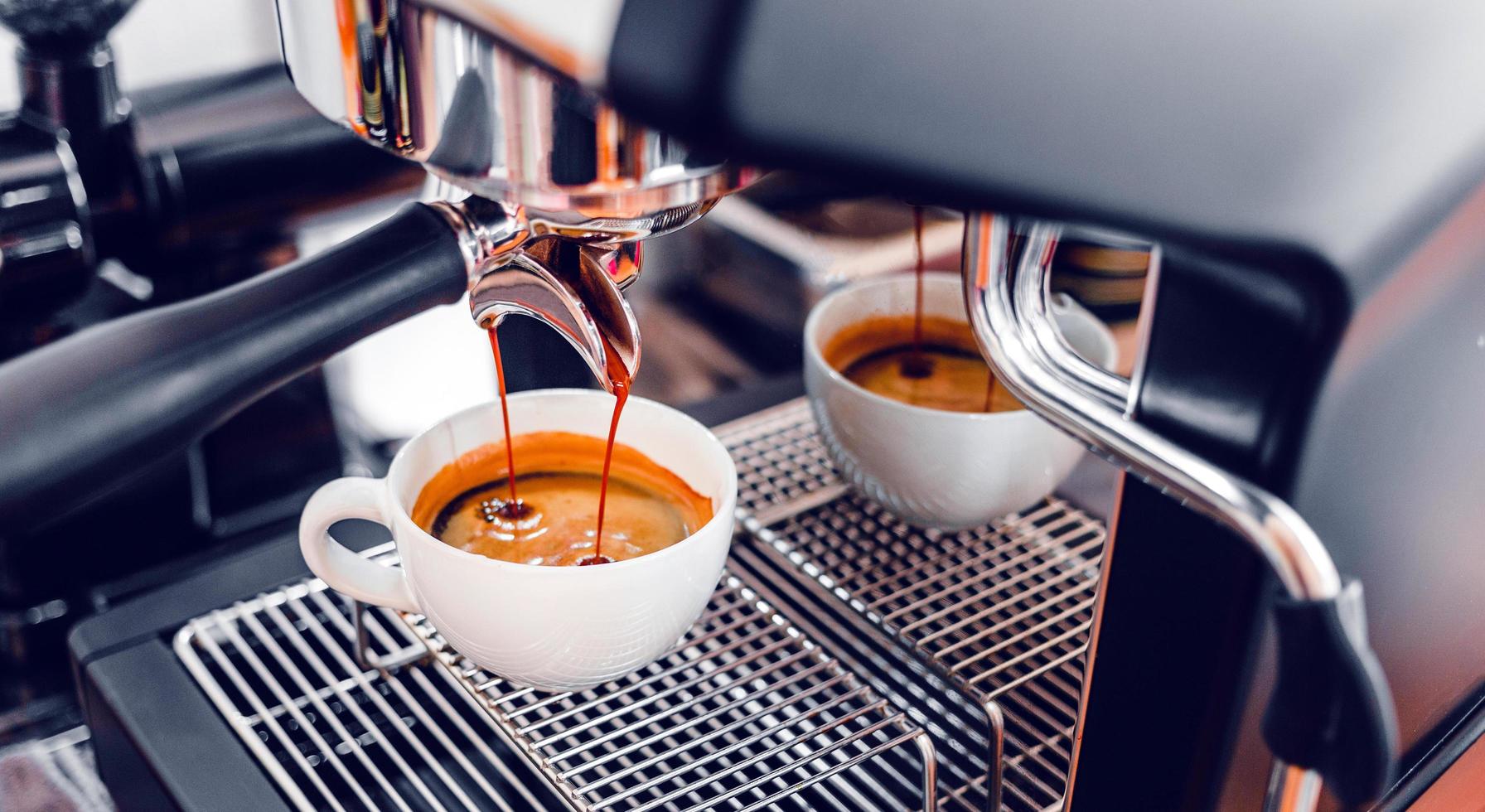 extracción de café de la máquina de café con un portafiltro que vierte café en una taza, café exprés que se vierte de la máquina de café en la cafetería foto