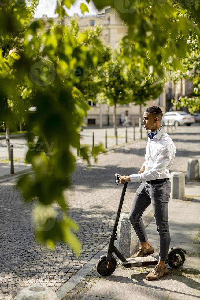 Young African American using electric scooter and waiting to cross the street photo