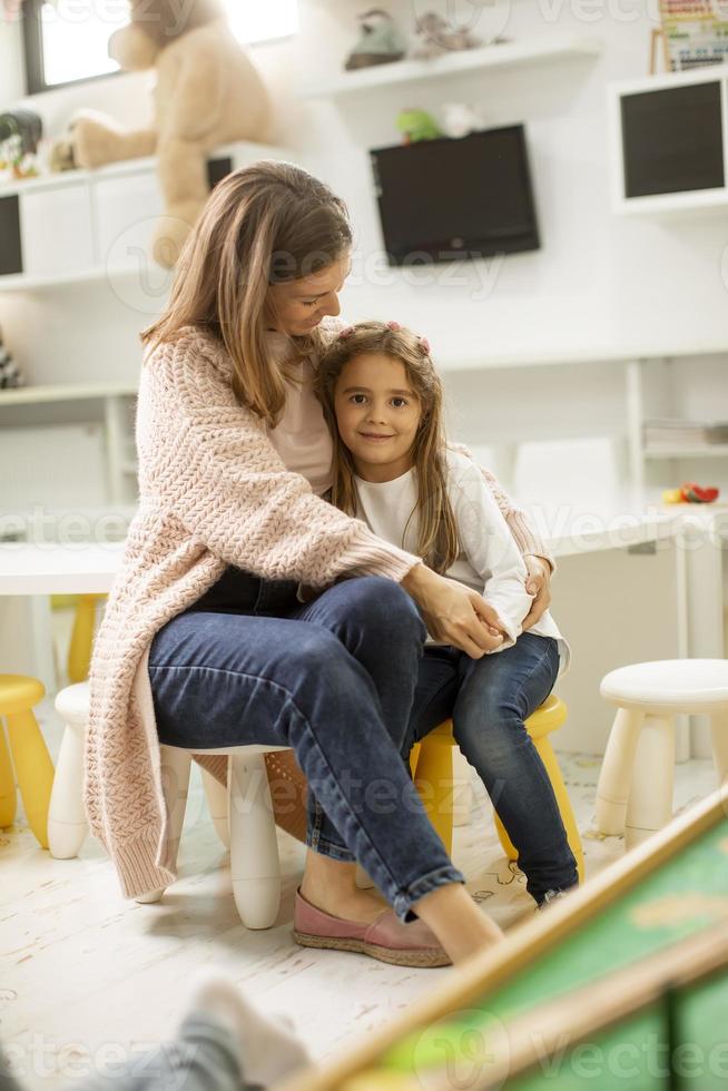 maestra de guardería hablando con una niña en el jardín de infantes foto