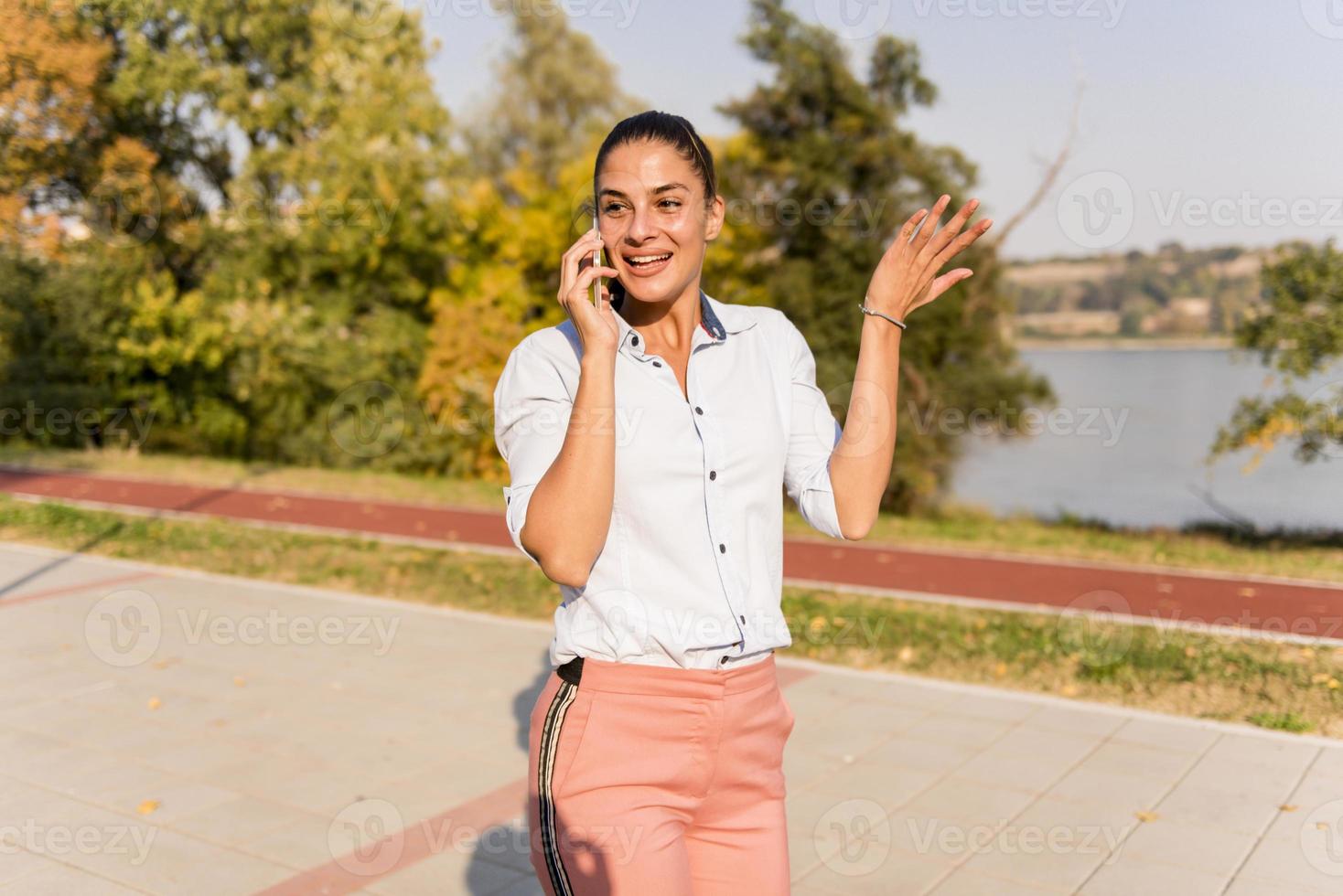 Young woman using mobile phone in the park by river photo