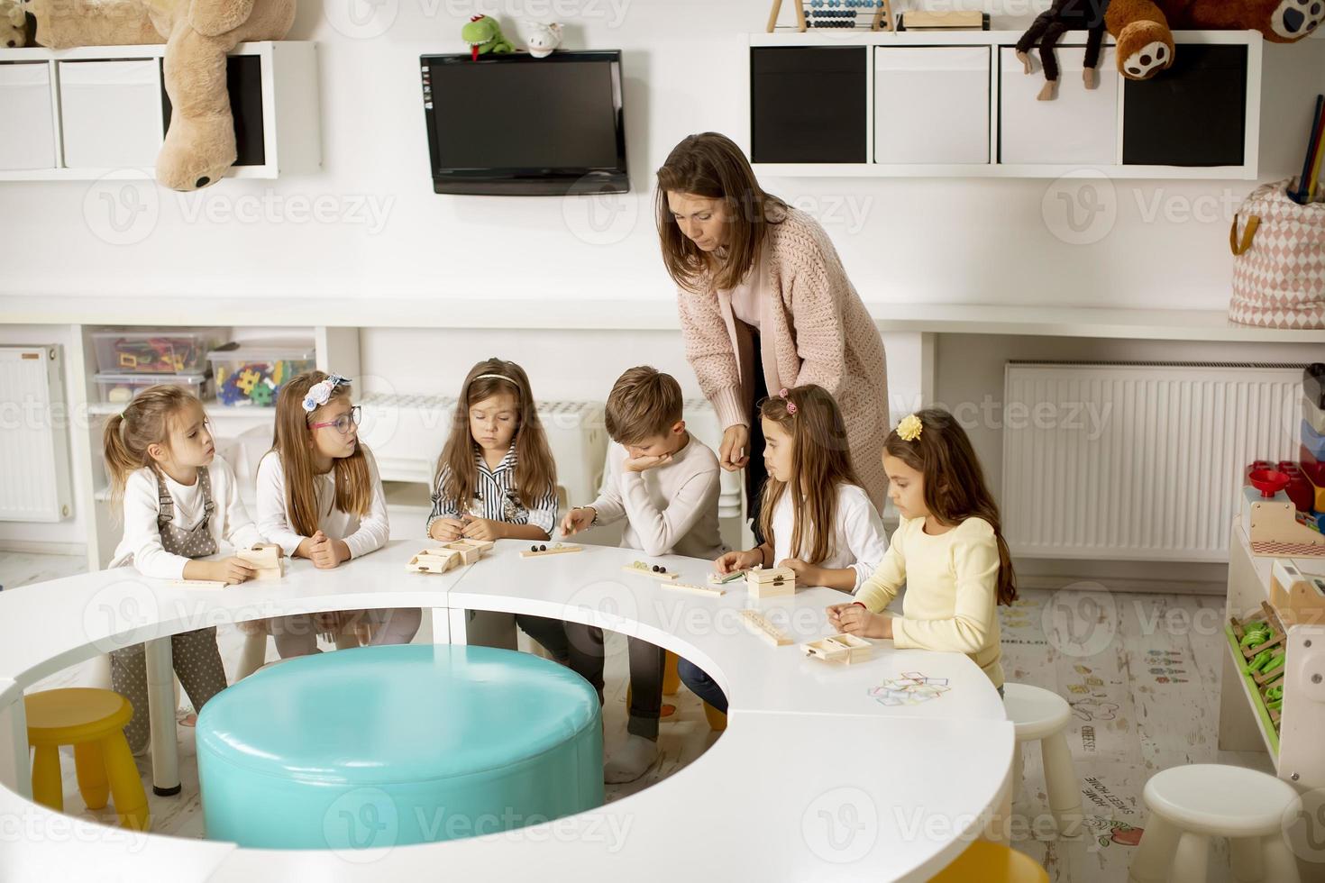 Group of cute little kids playing with preschool educational toys with kindergarden teacher photo