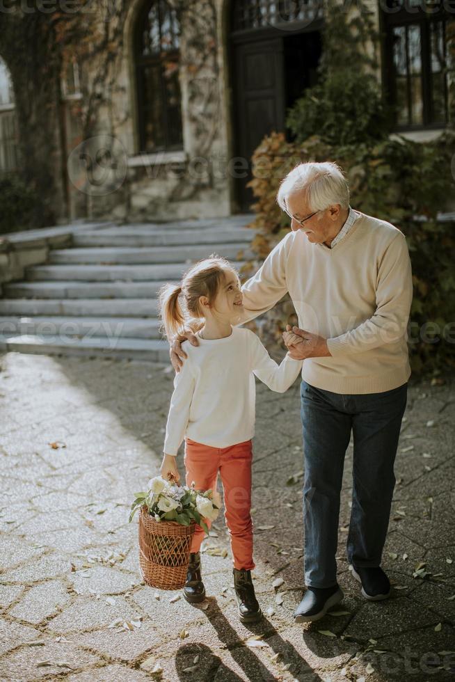 abuelo divirtiéndose con su nieta que sostiene una canasta llena de flores foto