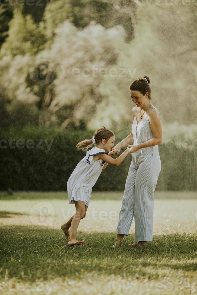 linda niña divirtiéndose en un césped con su madre foto