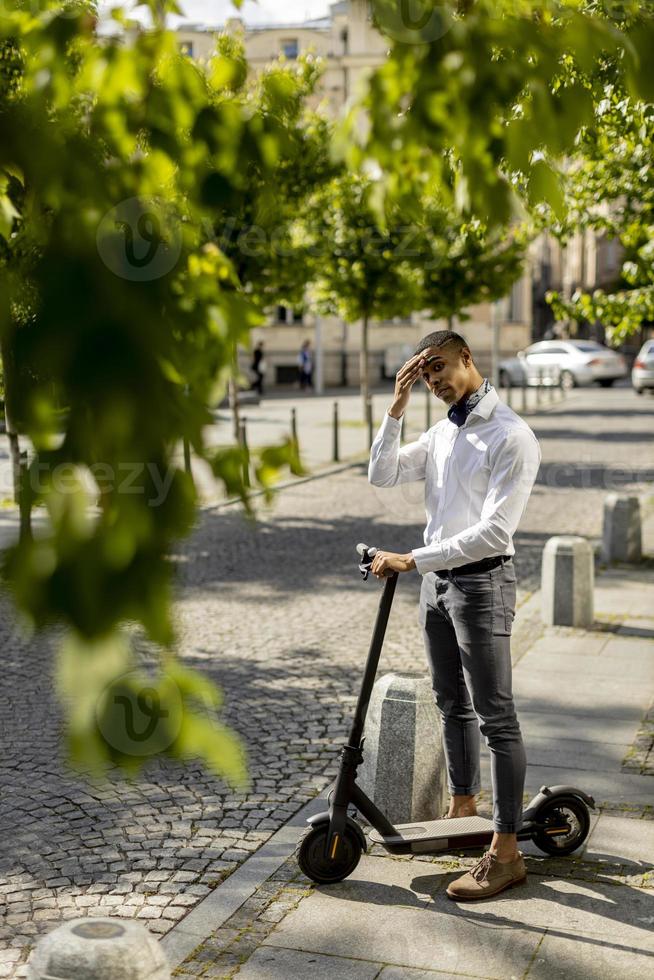 Young African American using electric scooter and waiting to cross the street photo