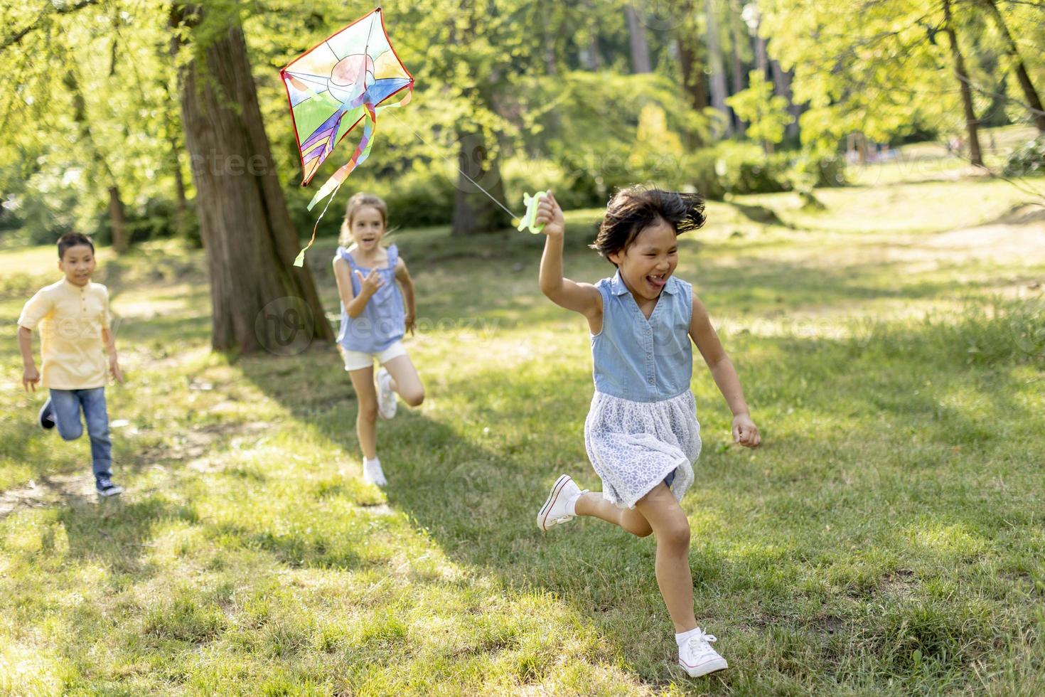 niña asiática corriendo alegremente con una cometa en el parque foto