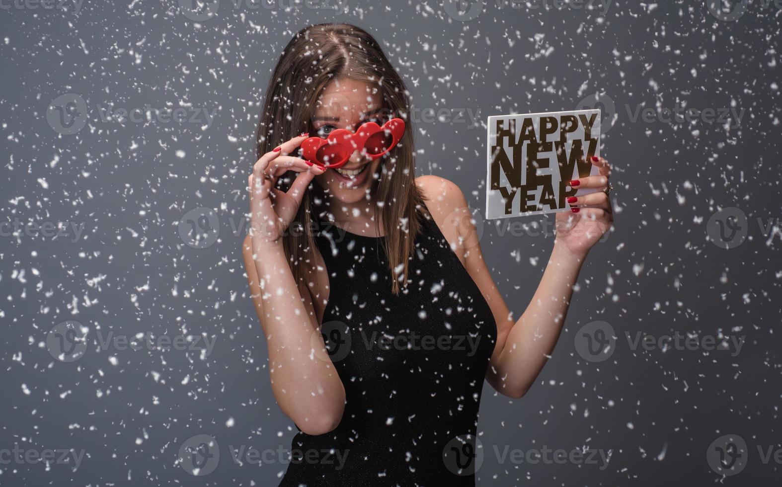 hermosa mujer celebrando el año nuevo con confeti y champán con cartel. aislado foto