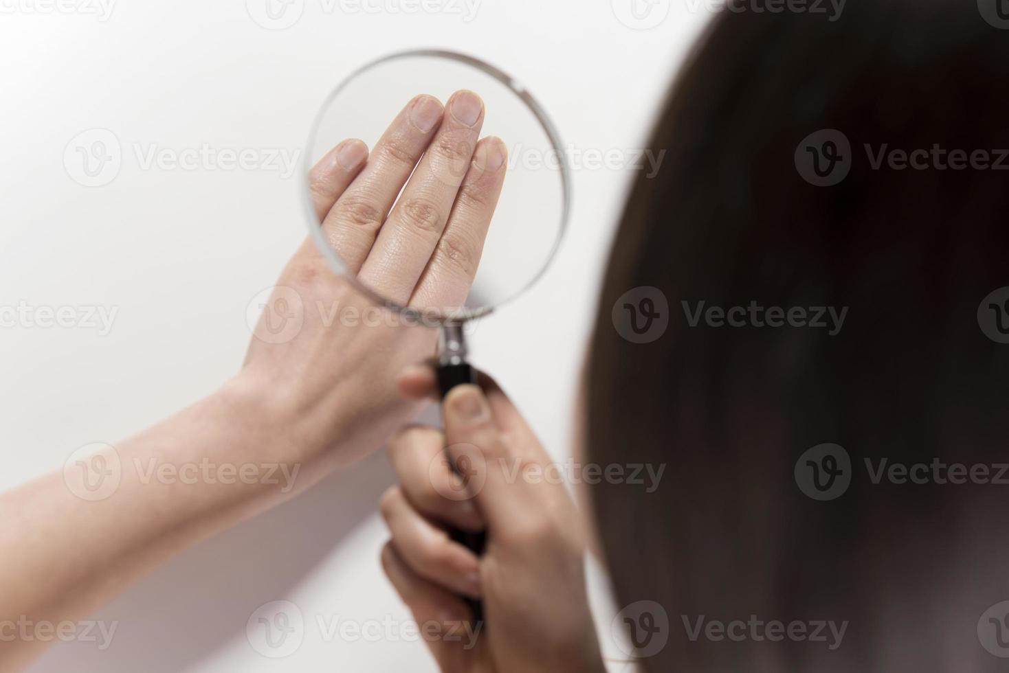 Woman looking her hand nails true magnifying glass Woman looking her hand nails true magnifying glass photo