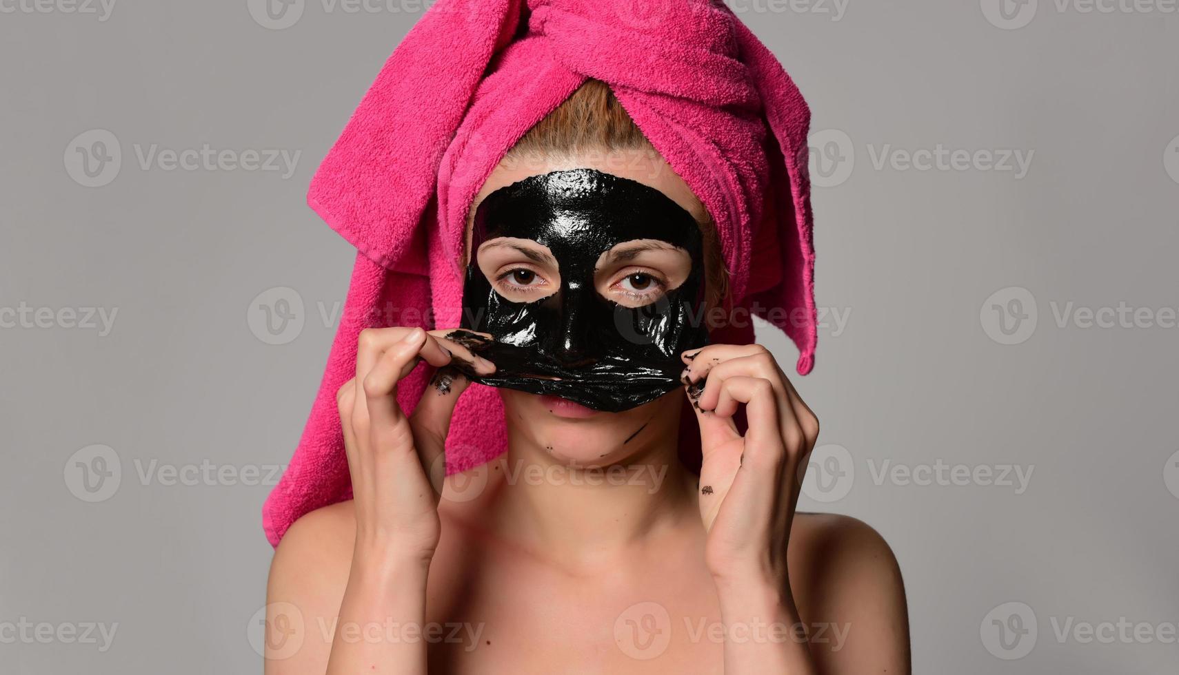 beautiful female model with black facial cosmetic mask. Isolated on gray background photo