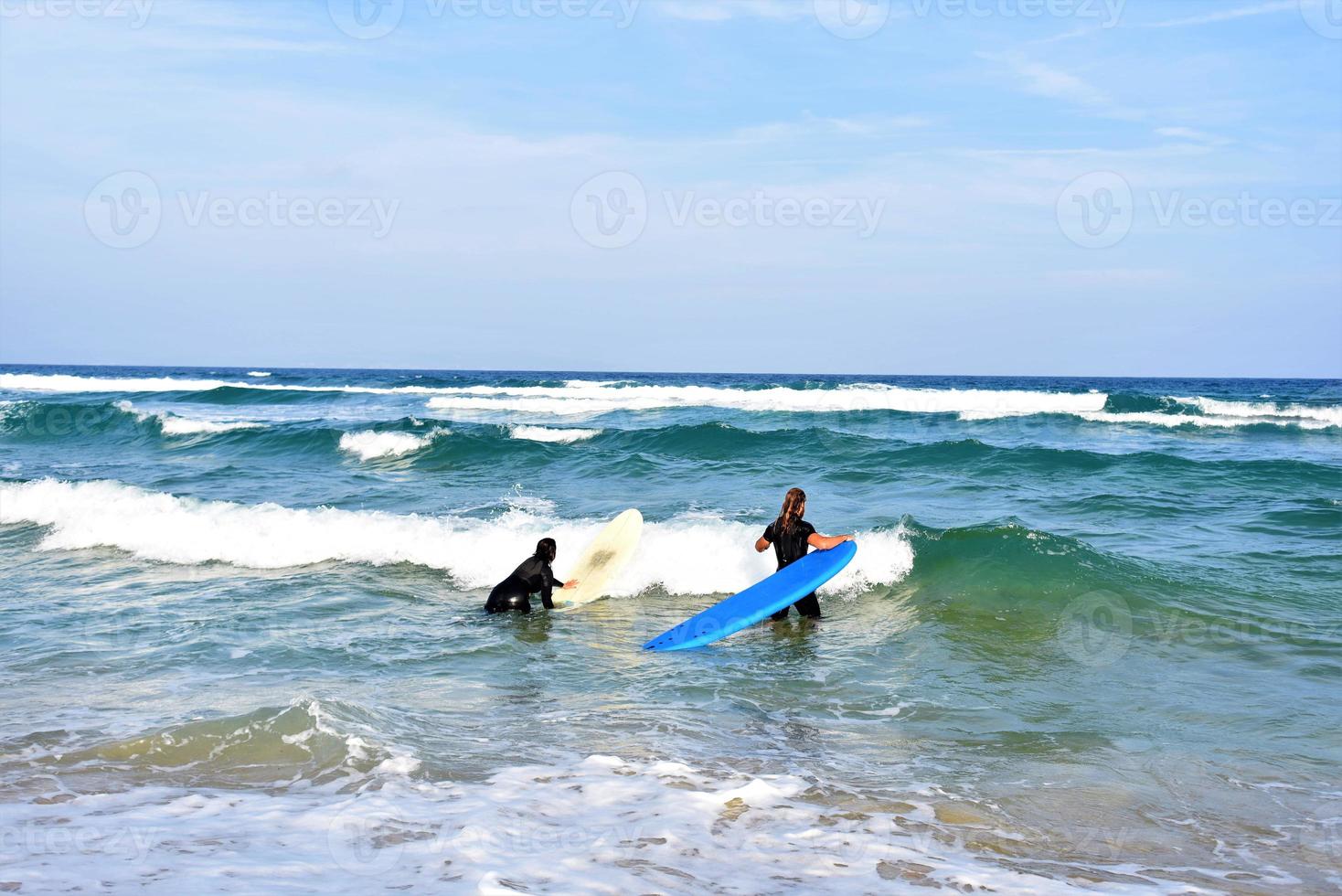 Surfers couple waiting for the high waves on beach - Sporty people with surf boards on the beach - Extreme sport and vacation concept photo