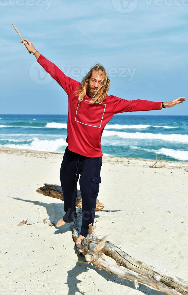 Man balancing on a log on the beach photo