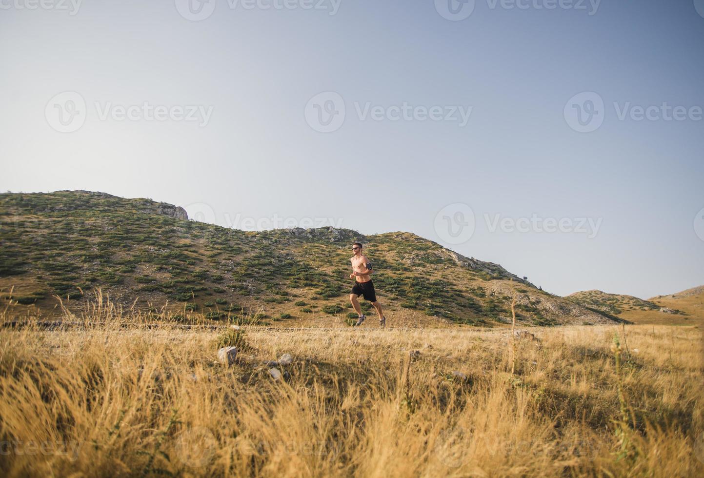 sporty man runner running on mountain plateau in summer photo