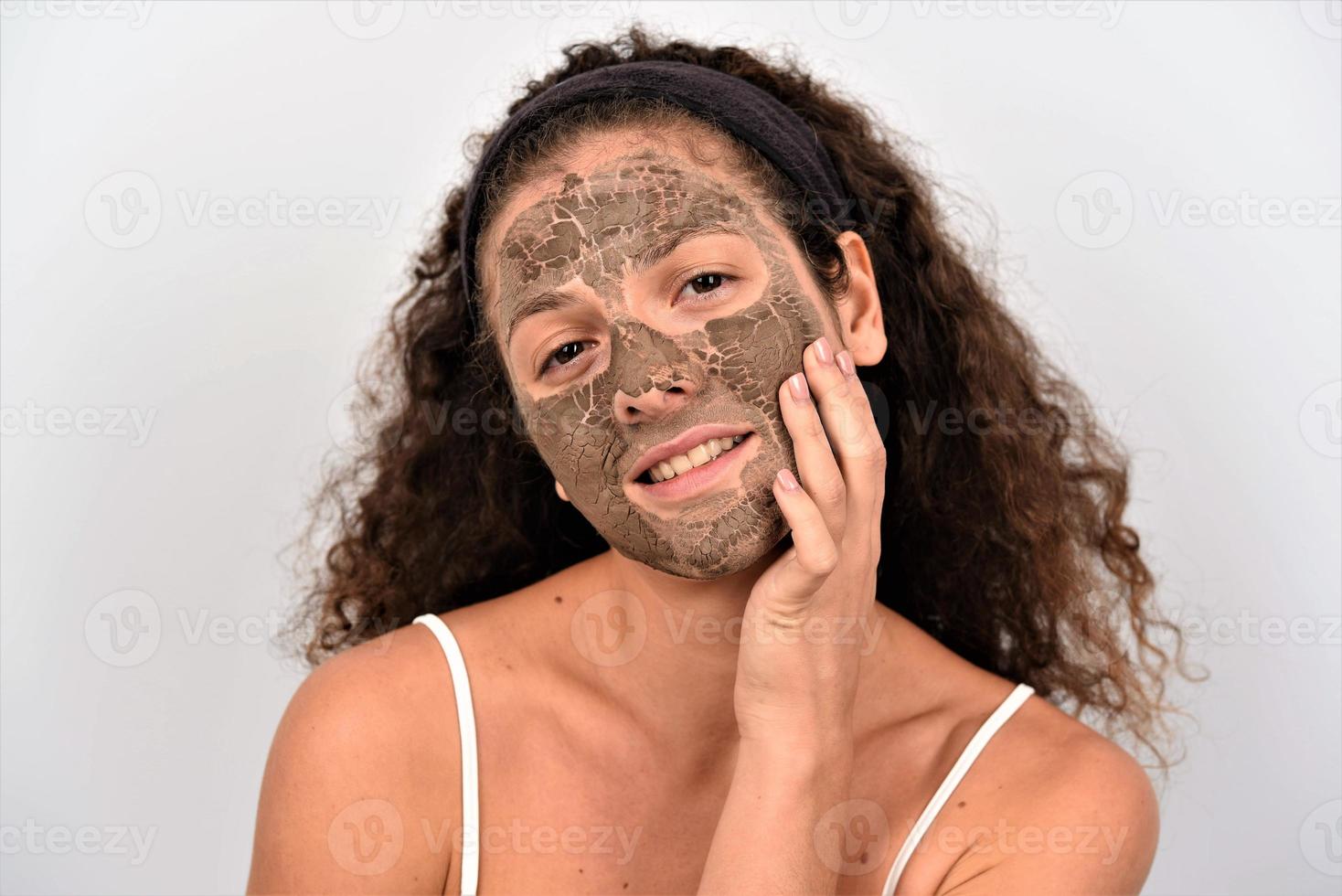 Beautiful woman removing clay facial mask from her face photo