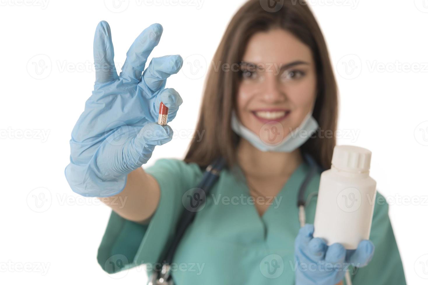 Portrait of professional female smiling doctor in green scrubs holding a brown pill bottle Medical Care photo