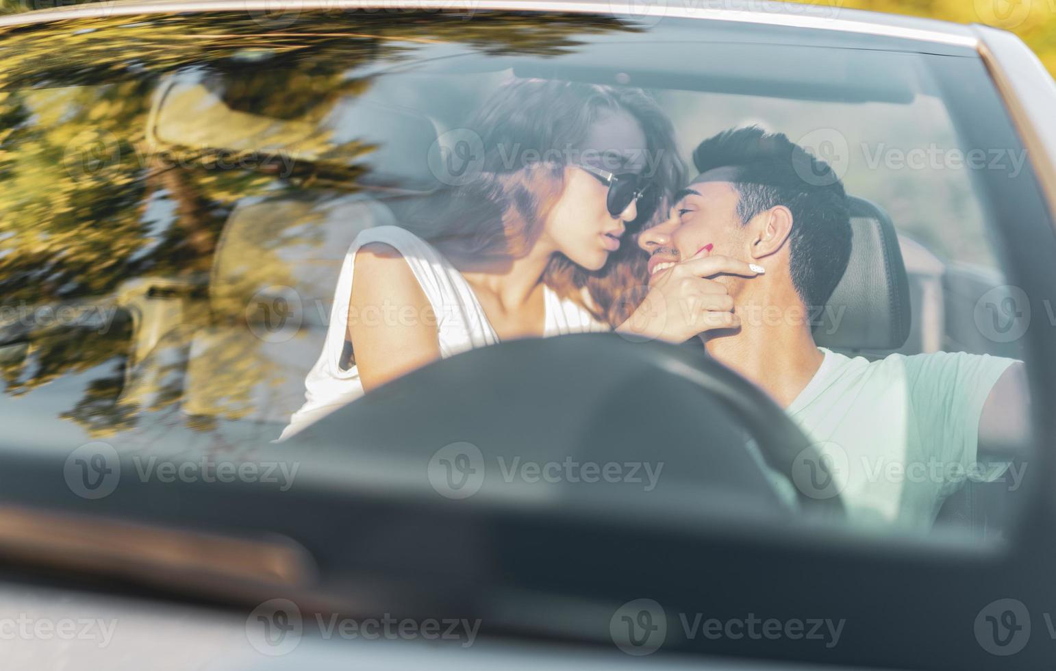 Friends having fun at car trip around the world. Couple in love with arms up on a convertible car. photo