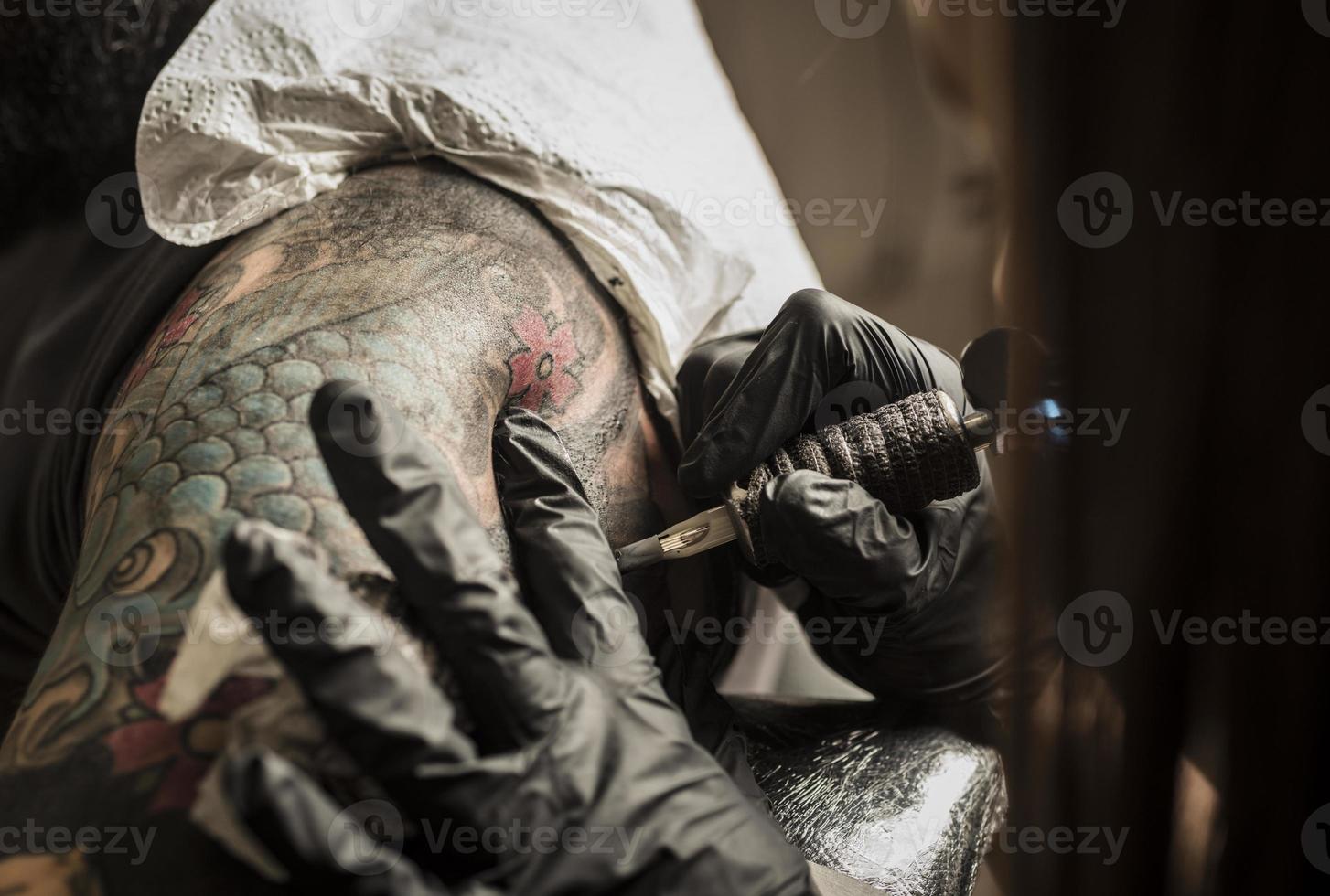 close up tattoo machine. Woman creating picture on hand with it in salon photo