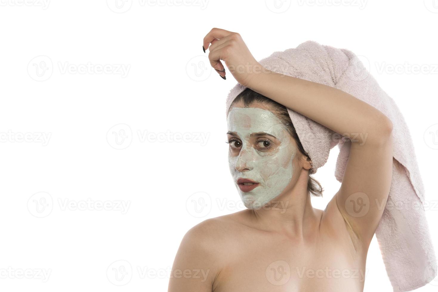 Beautiful woman having clay facial mask apply by beautician. photo