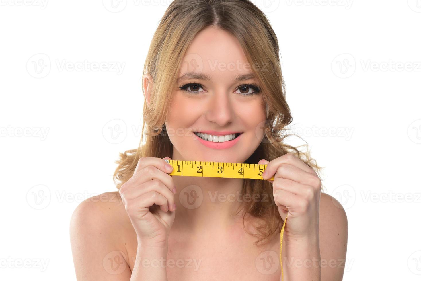 Portrait of beautiful woman with blond hair holding metering tape on white background photo