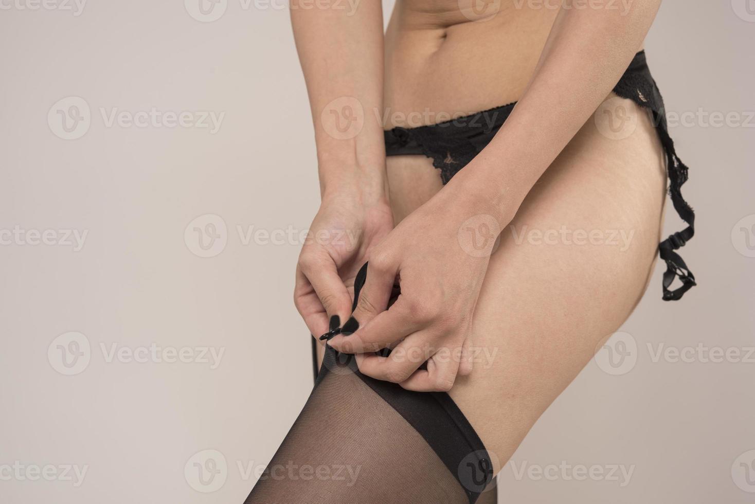 The legs of a sexy and beautiful young adult caucasian woman in black lingerie and stockings photo