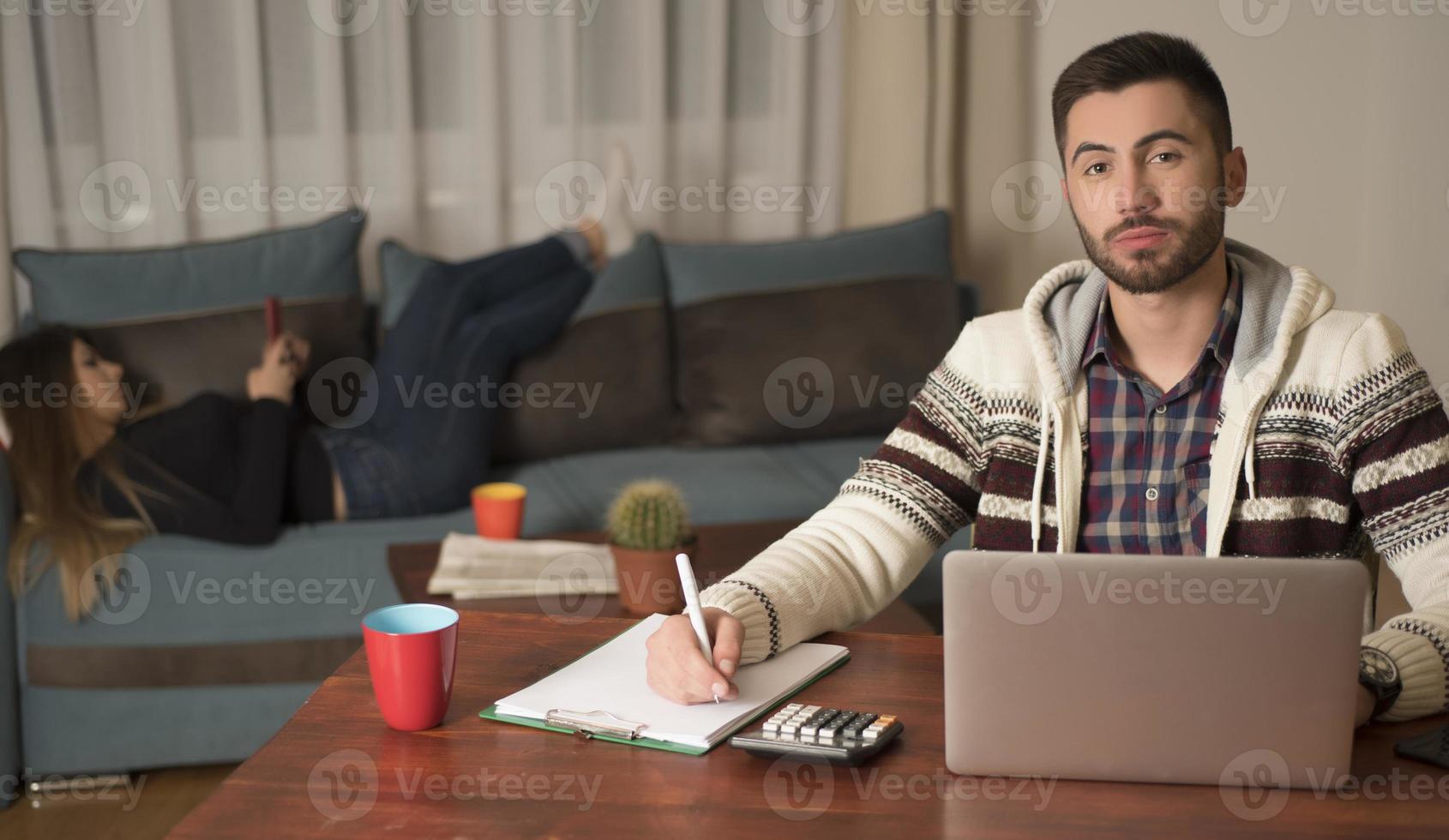 Young couple managing finances, reviewing their bank accounts using laptop computer. Woman and man doing paperwork together, paying taxes online on notebook pc photo