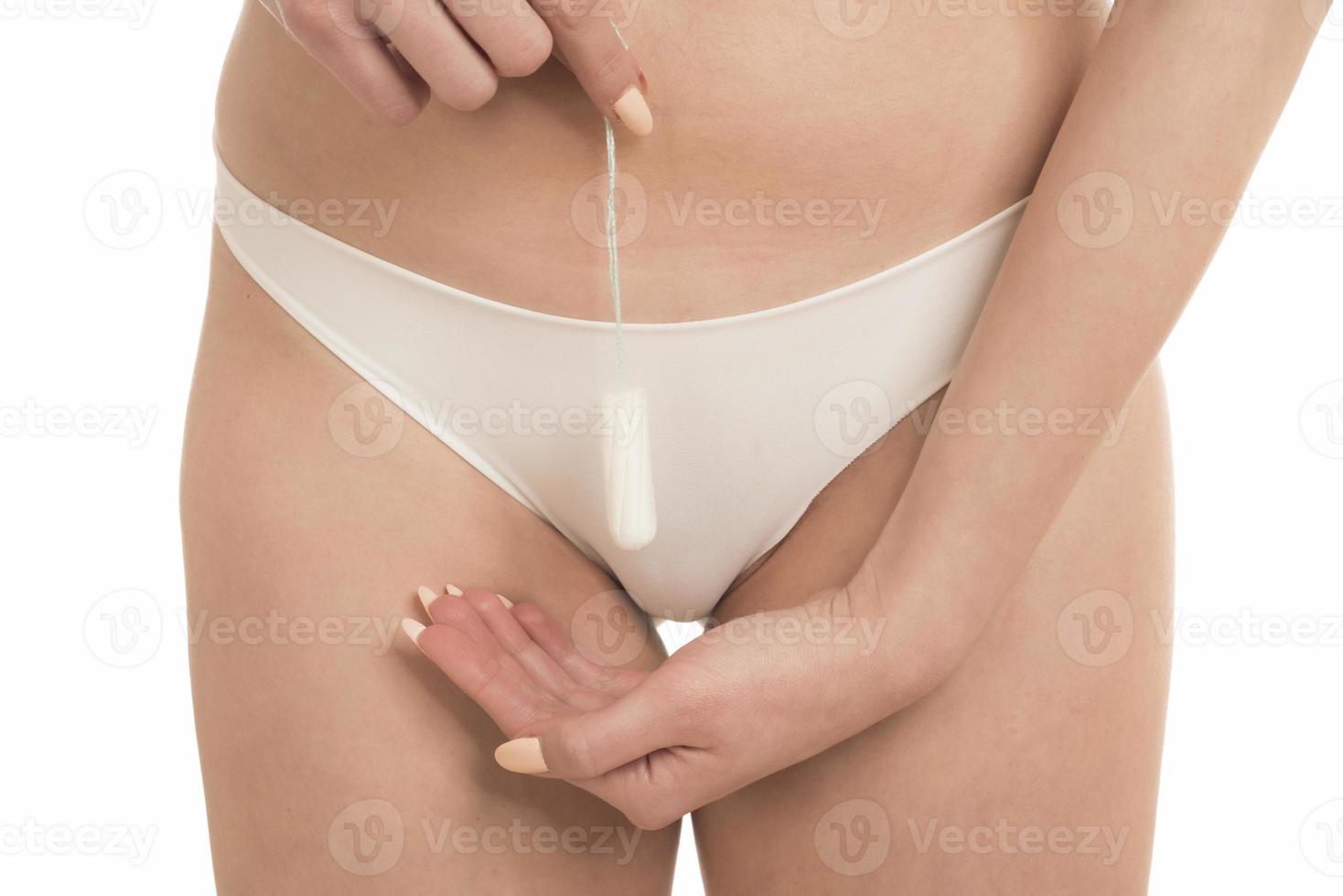 Female Period and Intimate Hygiene. Closeup cropped view of young woman in white panties holding tampon photo