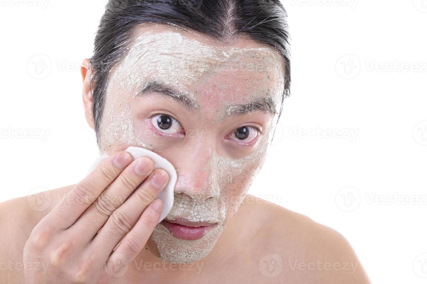 retrato de un hermoso joven que se quita una máscara facial, un retiro para el cuidado de la piel de la cara y el cuerpo. foto