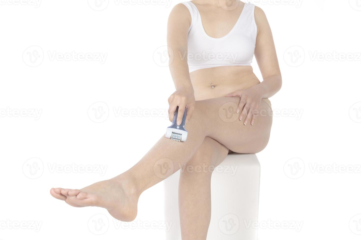 Shave legs electric epilator. Woman depilates her leg with an electric epilator device in the bathroom. Female shaves legs with white depilator. Removal hair. Close up, woman's leg shaving. photo