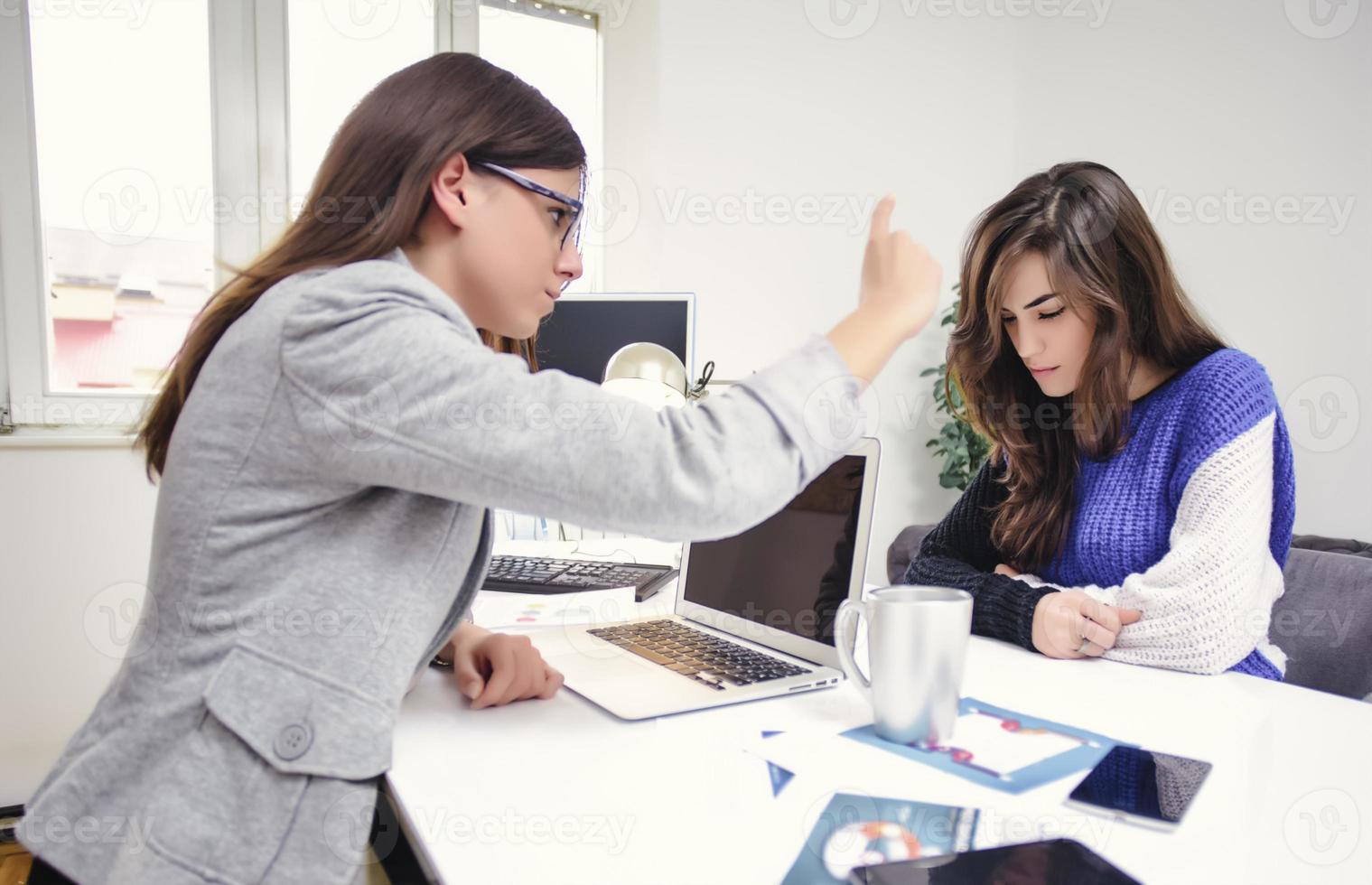 Portrait of aggresive boss scolding and shouting at employees threatening with a finger photo