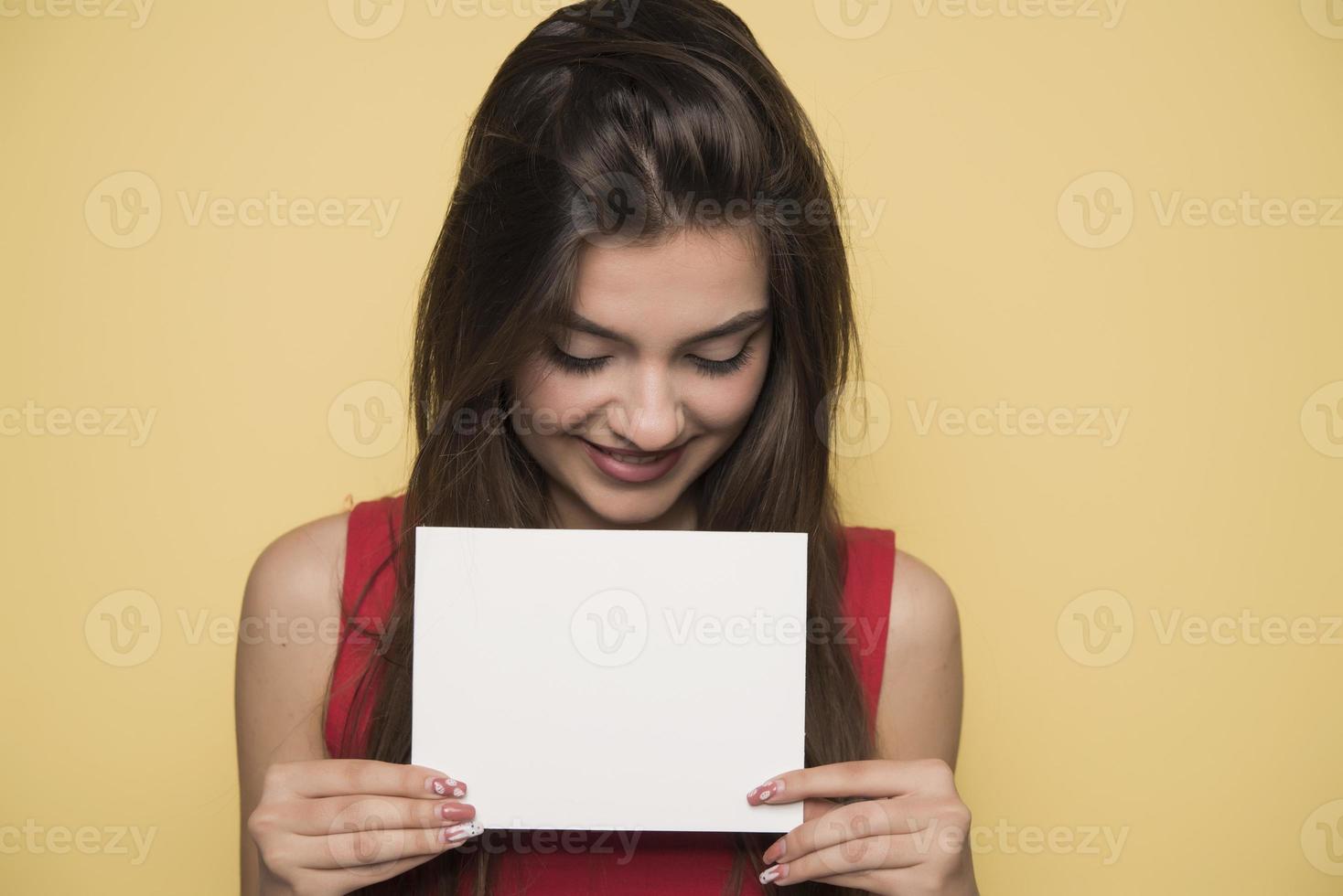 joven mujer sonriente sosteniendo una hoja de papel en blanco para publicidad foto