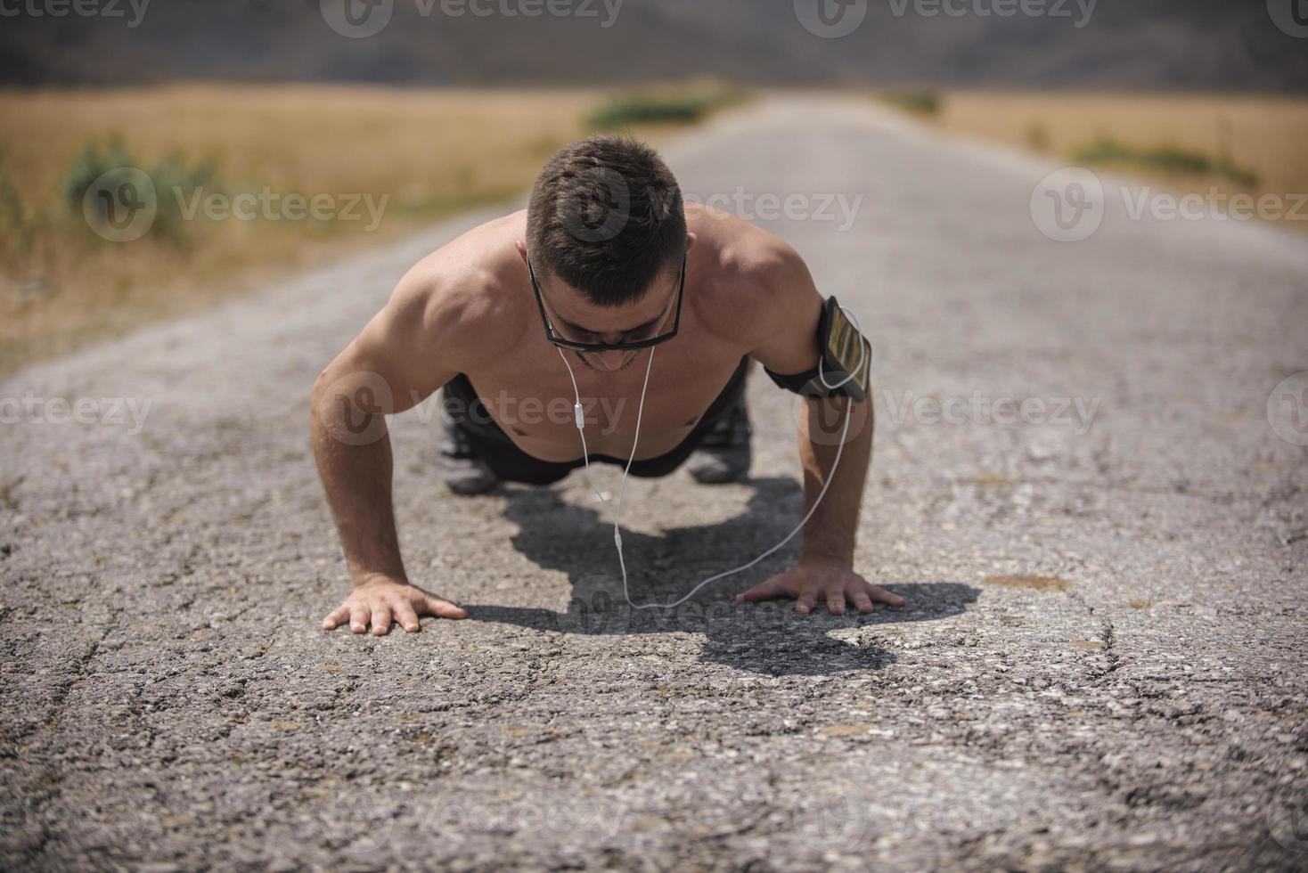 Male athlete exercising push up outside in sunny sunshine. Fit shirtless male fitness model in crossfit exercise outdoors. Healthy lifestyle concept. photo