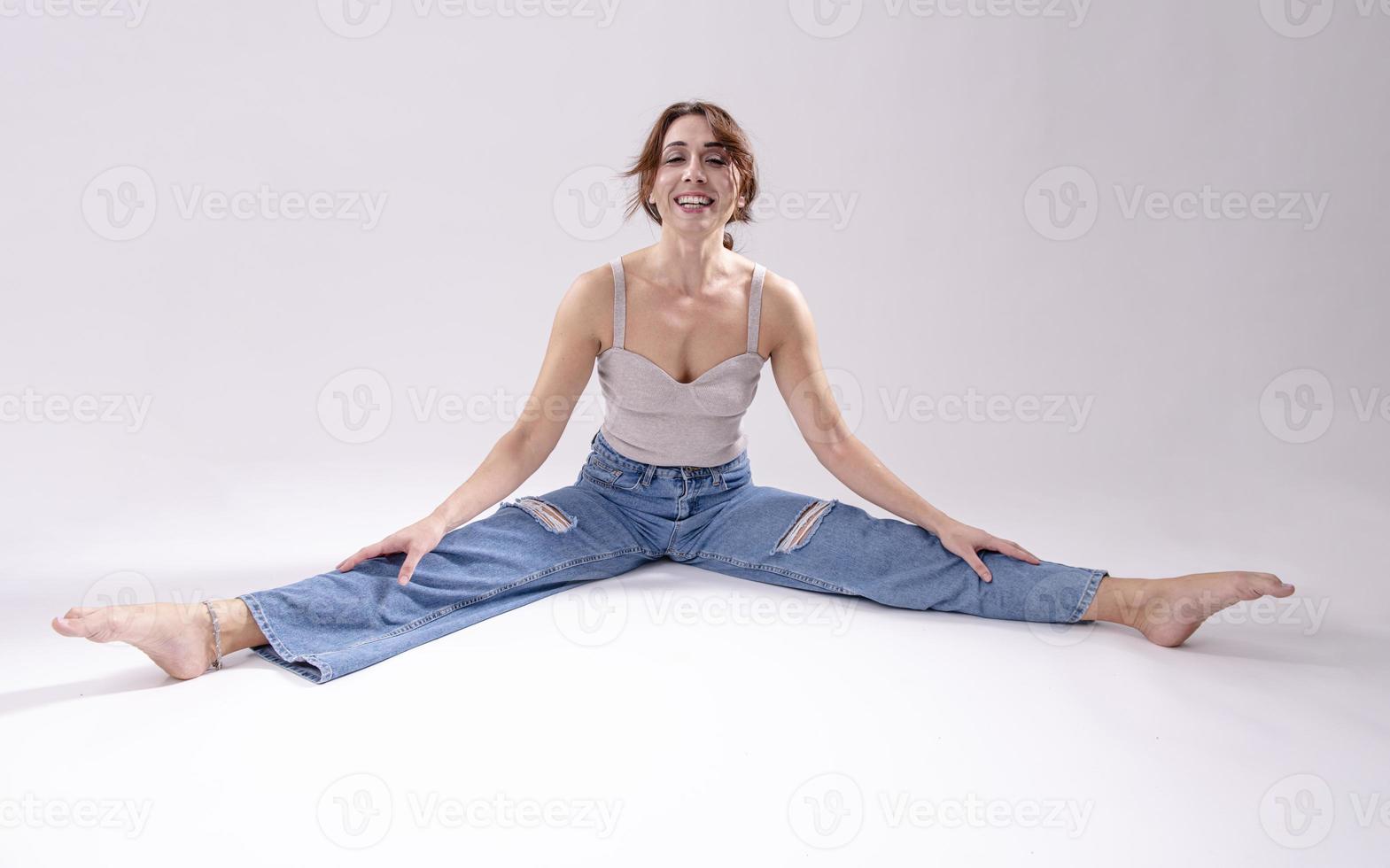 retrato de una hermosa joven con un cuerpo atlético y flexible haciendo estiramientos de piernas. aislado foto