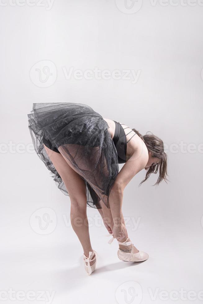 Young and incredibly beautiful ballerina is posing and dancing in a white studio full of light. The photo greatly reflects the incomparable beauty of a classical ballet art.