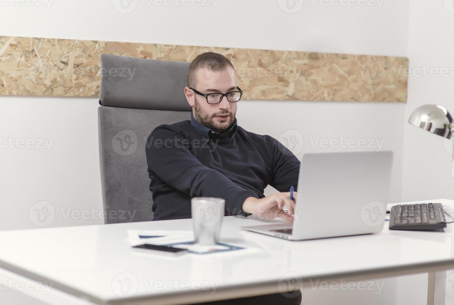 Young business man working at home with laptop and papers on desk photo