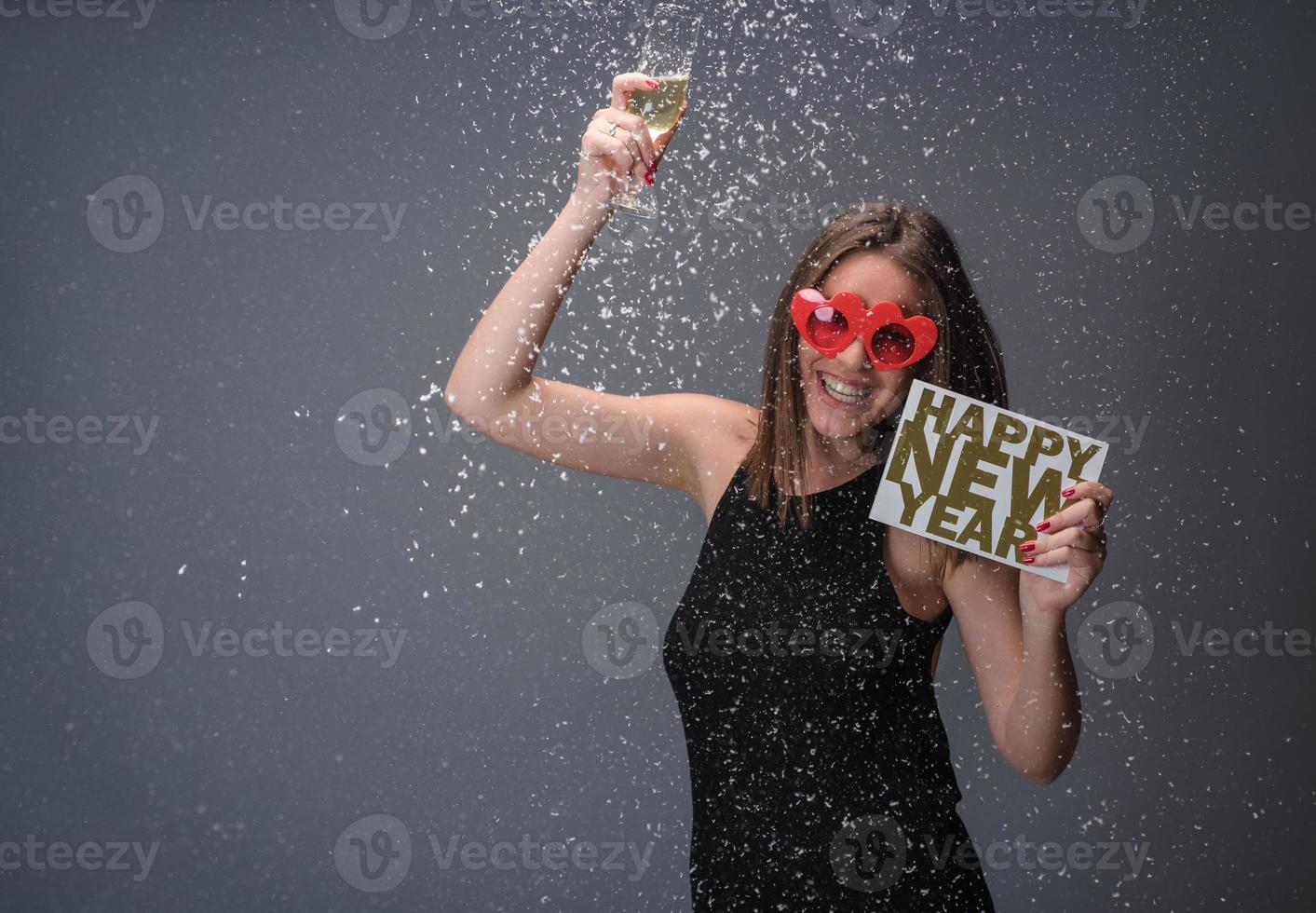 hermosa mujer celebrando el año nuevo con confeti y champán con cartel. aislado foto