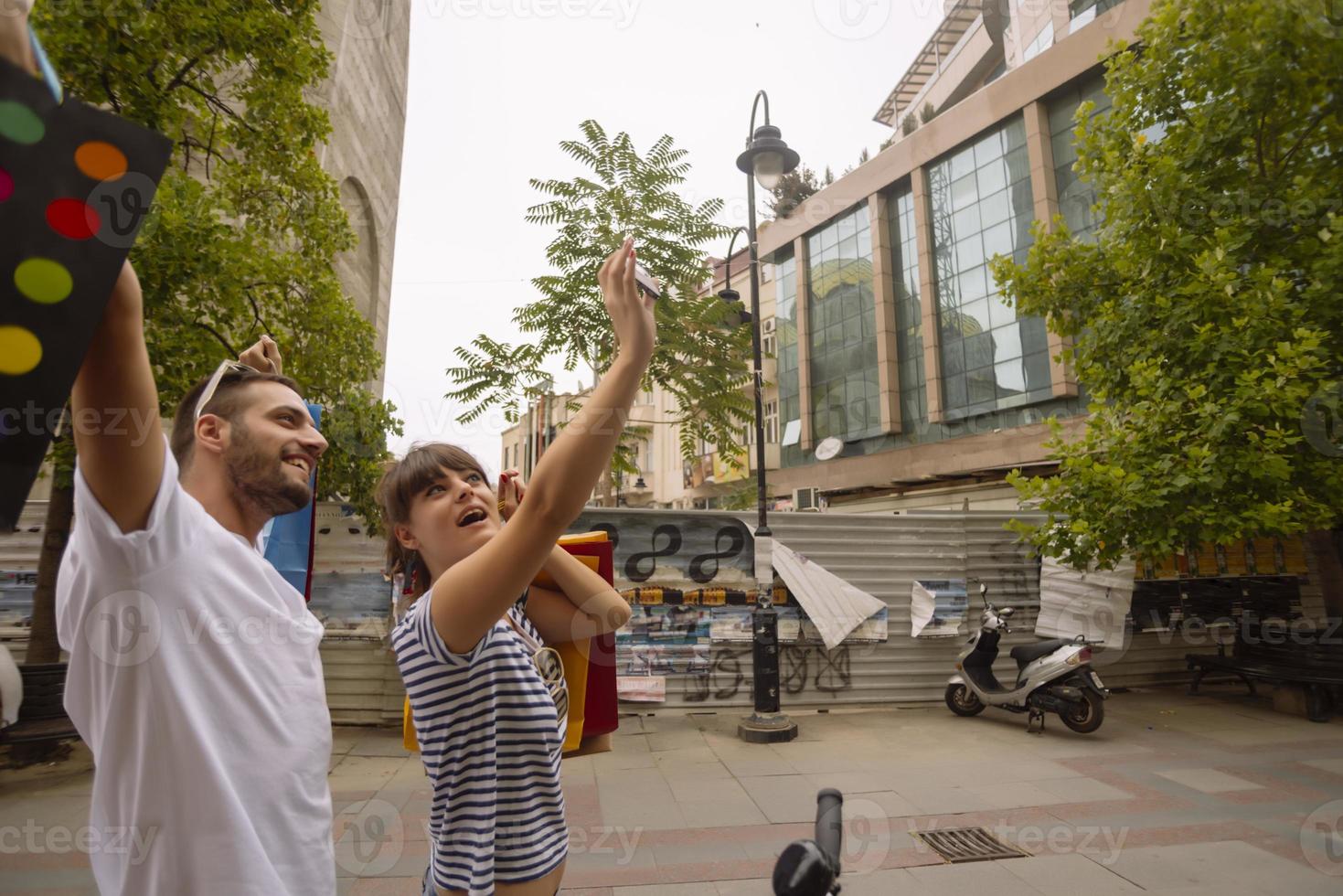 Portrait of cheerful Caucasian young couple man and woman holding many paper bags after shopping while walking and talking on street. Happy family couple with packages outdoor. Buying concept photo