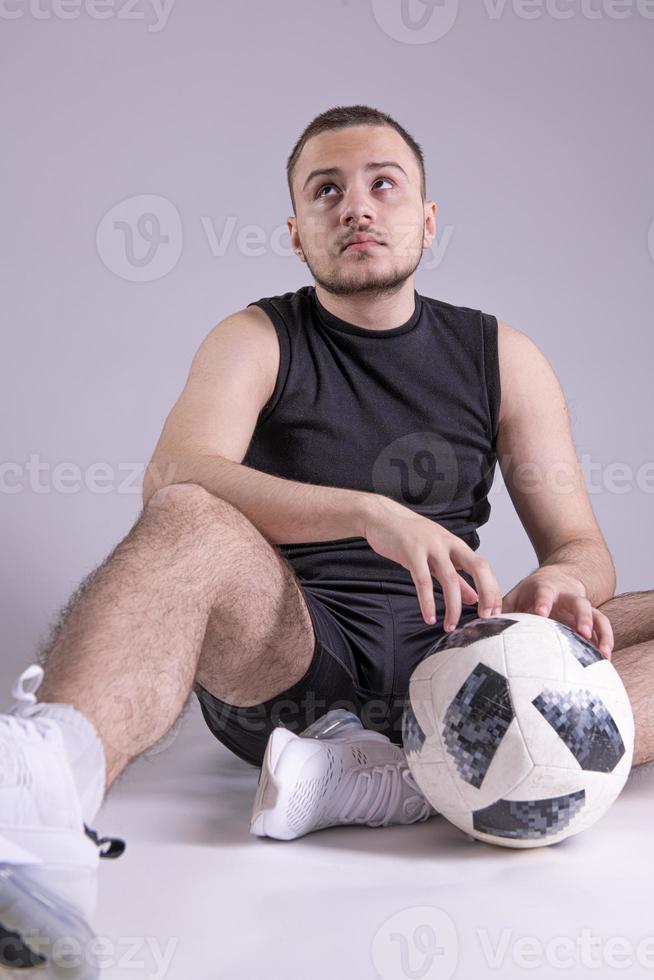 Young happy man 20s fan  support football sport team hold in hand soccer ball. isolated on plain solid gray background photo