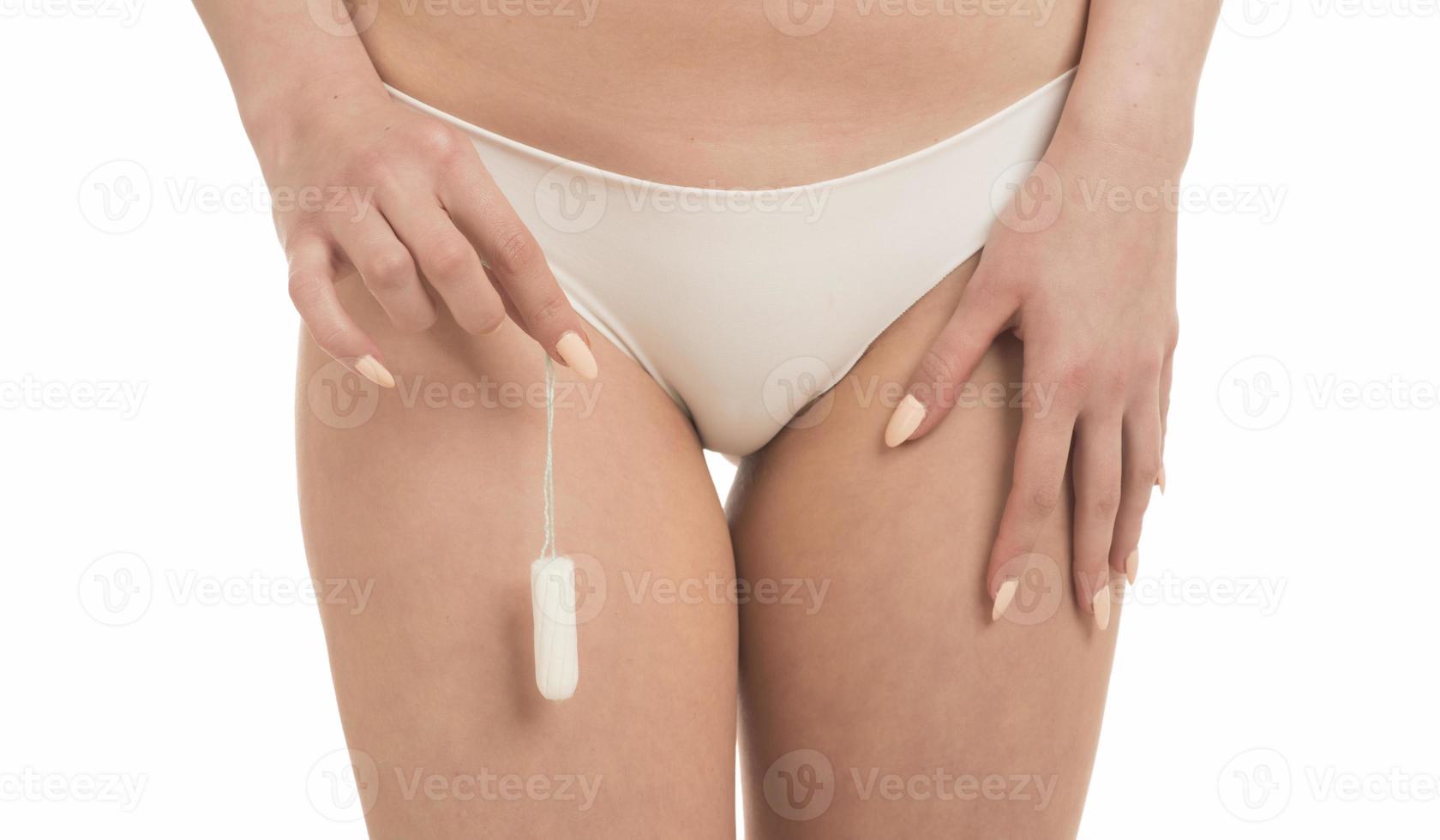 Female Period and Intimate Hygiene. Closeup cropped view of young woman in white panties holding tampon photo