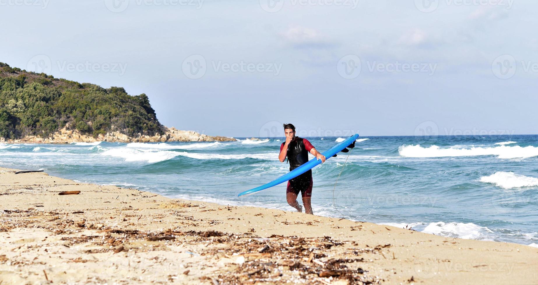 A man is standing with a surf in his hands on the sea shore. photo