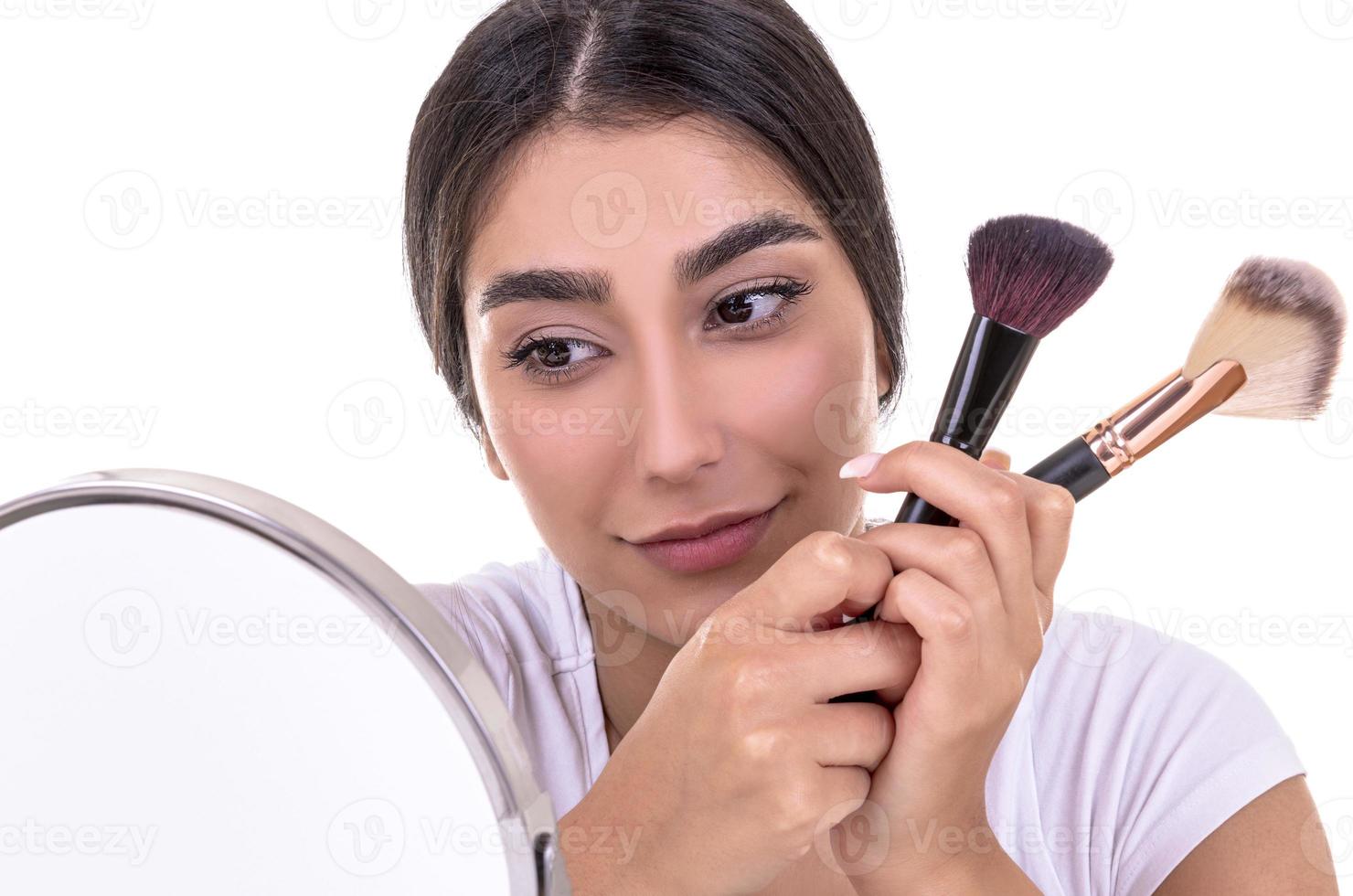 beautiful brunette pouting makeup with a brush on her face. beauty concept. isolated photo