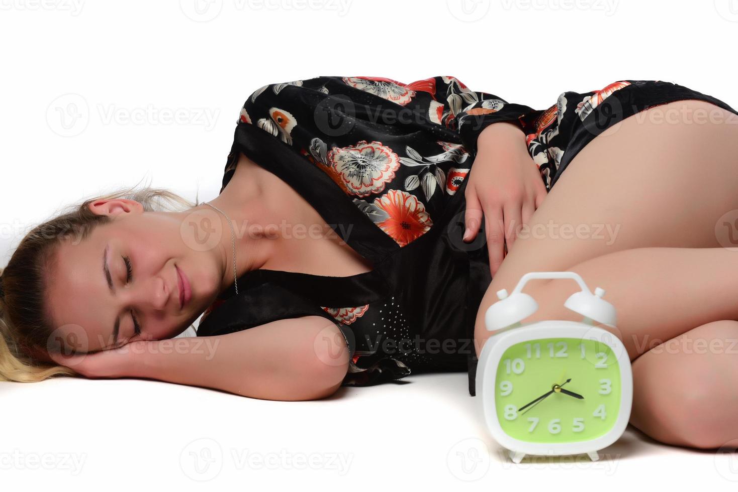 Happy young woman holding clock over isolated white background photo
