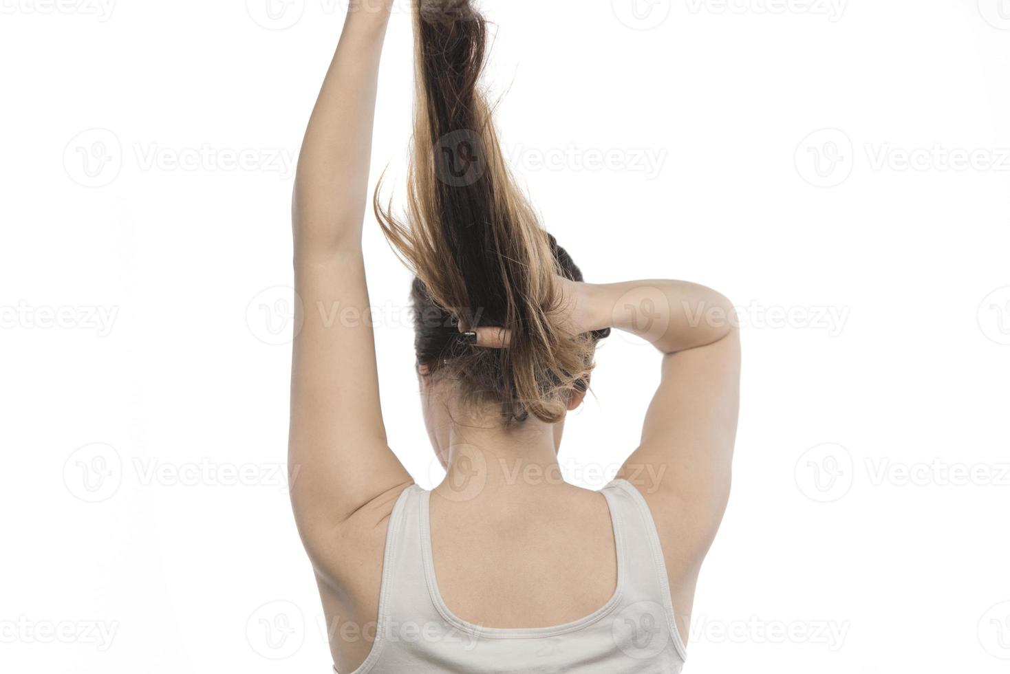 Female model arranging her hair. Woman tying hair in a bun. photo