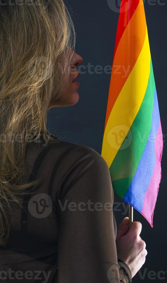 Lesbian woman holding rainbow flag isolated on black background. LGBT International symbol of the lesbian, gay, bisexual and transgender community. photo