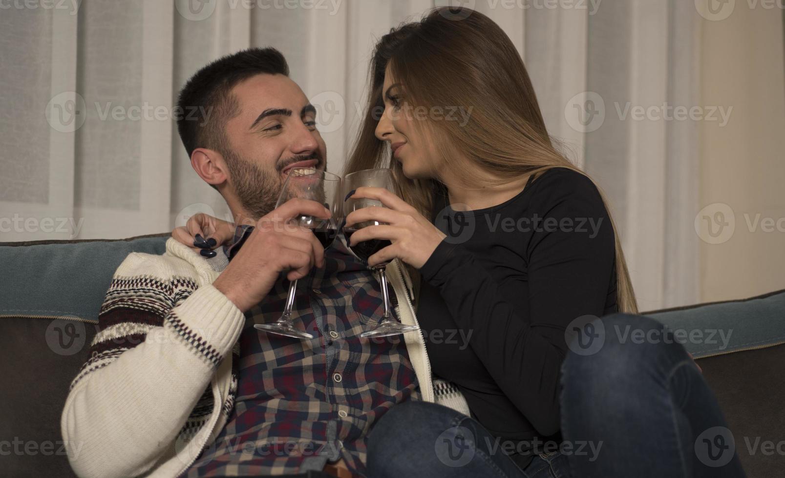 alegre pareja feliz bebiendo vino en casa. noche de cita en casa, tintineo de copas de vino. foto